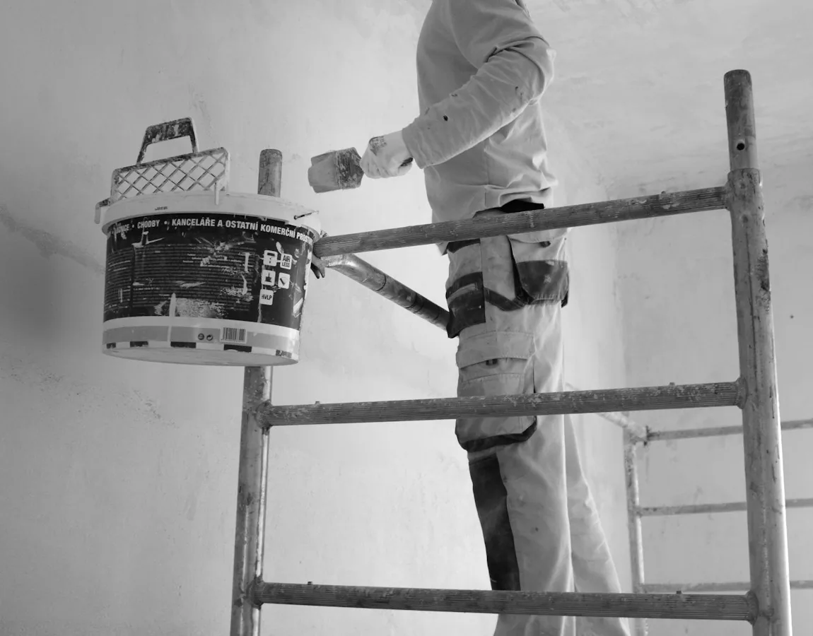 Pintor alisando y pintando paredes en una vivienda